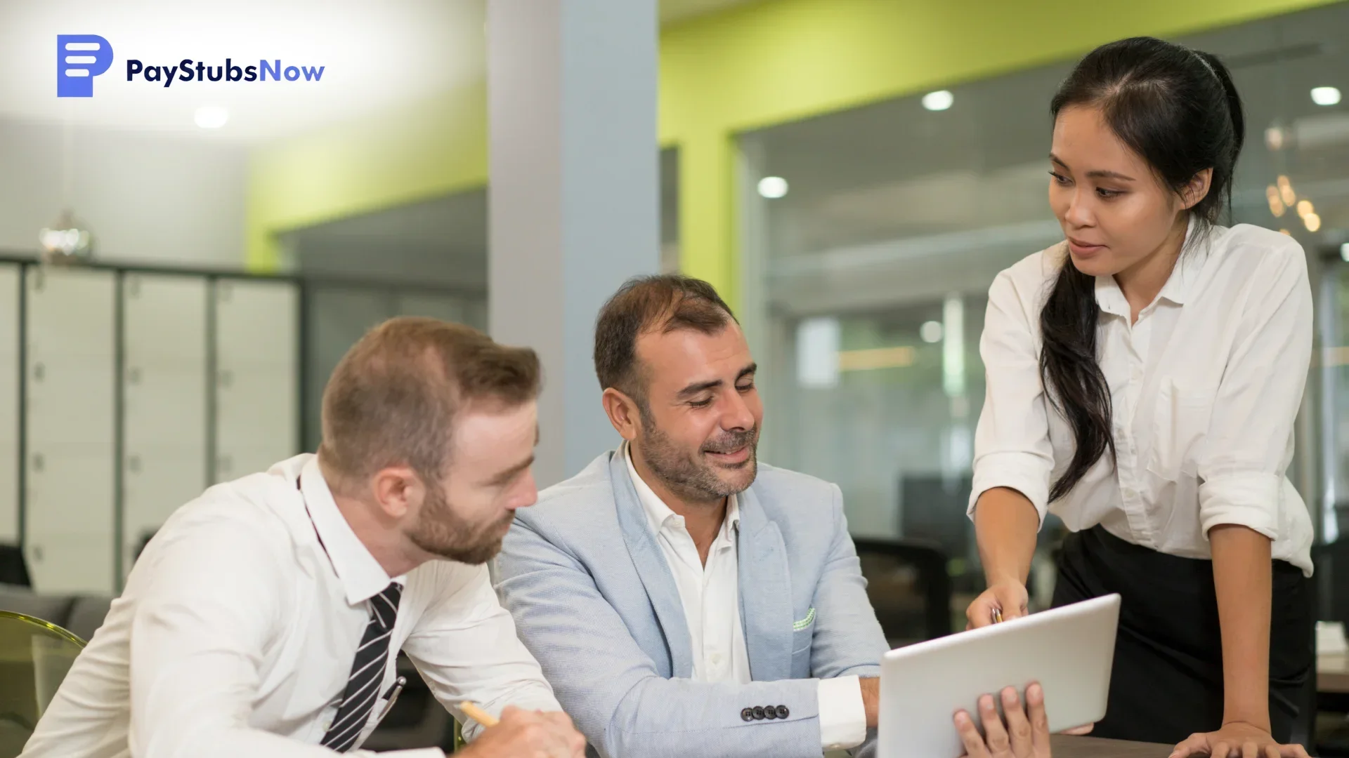 Three business professionals gathered around a laptop in an office