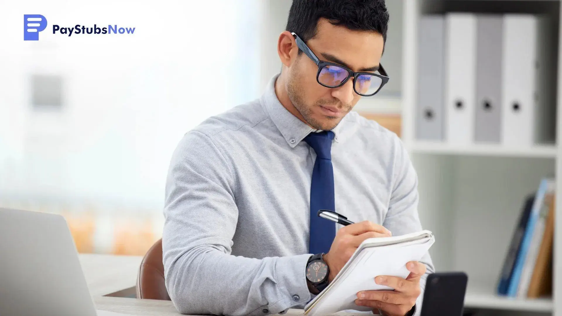 A focused man in glasses taking notes to understand what is a W-2 form and who gets one.